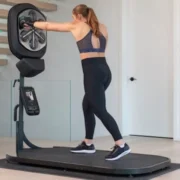 A woman is standing on a treadmill in a liteboxer fitness bundle in a living room.