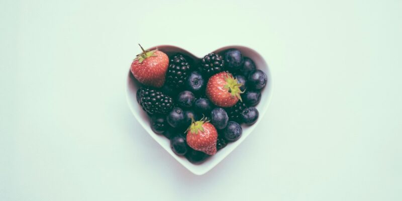 A bowl of berries in the shape of a heart.