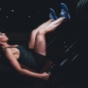 A woman is sitting on a machine in a gym.