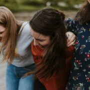 A group of women laughing together on a wooden boardwalk.