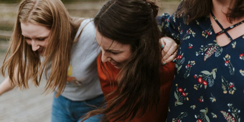 A group of women laughing together on a wooden boardwalk.