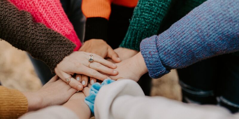 A group of people putting their hands together in a circle.