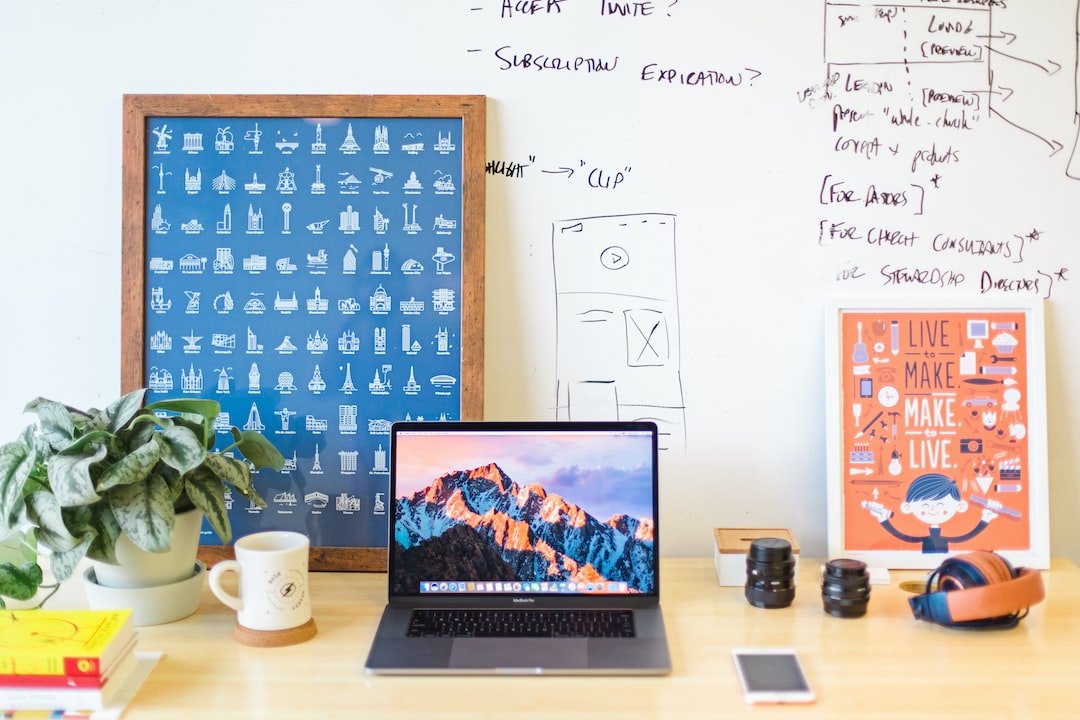 A desk with a laptop, a notebook, and a poster.