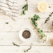 A bowl of herbs and lemons on a wooden table.