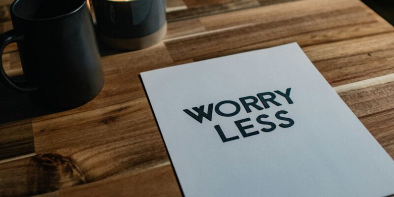 A piece of paper with the word worry less on it on a wooden table.