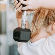 A woman lifting a dumbbell in a gym.