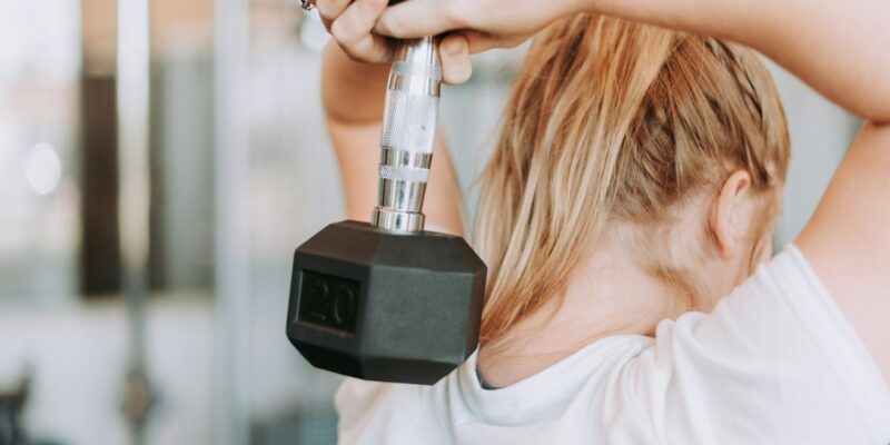 A woman lifting a dumbbell in a gym.