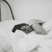 A black and white photo of a woman sleeping in bed.