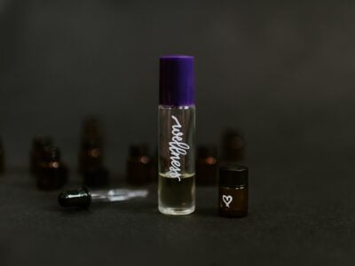 A bottle of essential oil with a purple bottle next to it.
