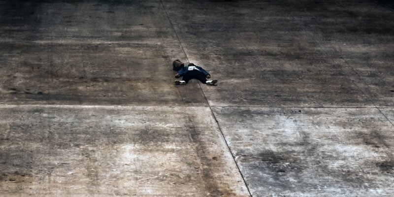 A person laying on a concrete floor.