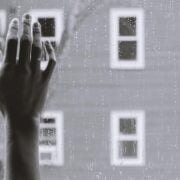 A black and white photo of a hand reaching out of a window.