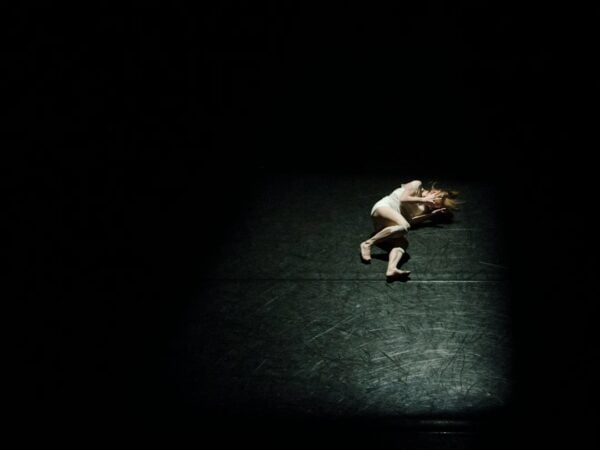 A woman laying on the floor in the dark.