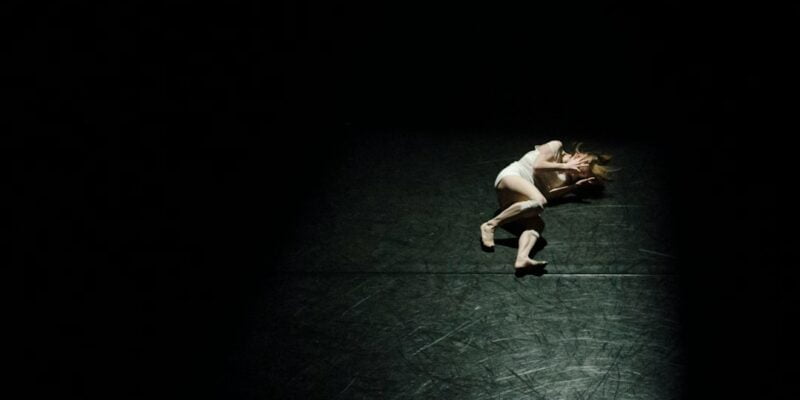 A woman laying on the floor in the dark.