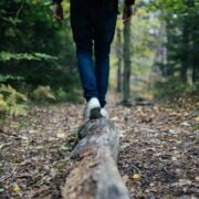 A person walking on a log in the woods.