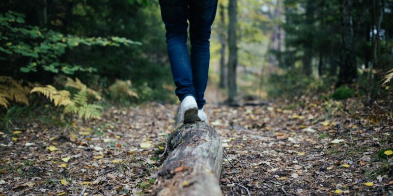 A person walking on a log in the woods.