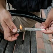 A person holding a lighter while sitting on a bench.