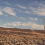 Wind turbines on a hillside with a blue sky.