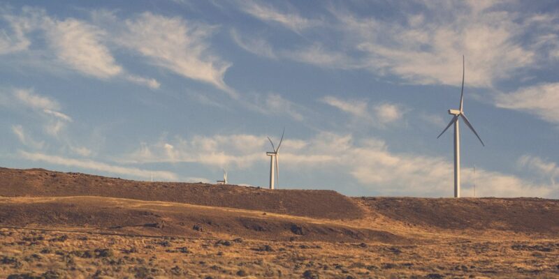 Wind turbines on a hillside with a blue sky.