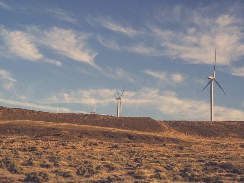 Wind turbines on a hillside with a blue sky.