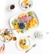 A woman is eating a plate of fruit and yogurt.