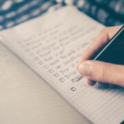 A person writing on a notebook with a pen.