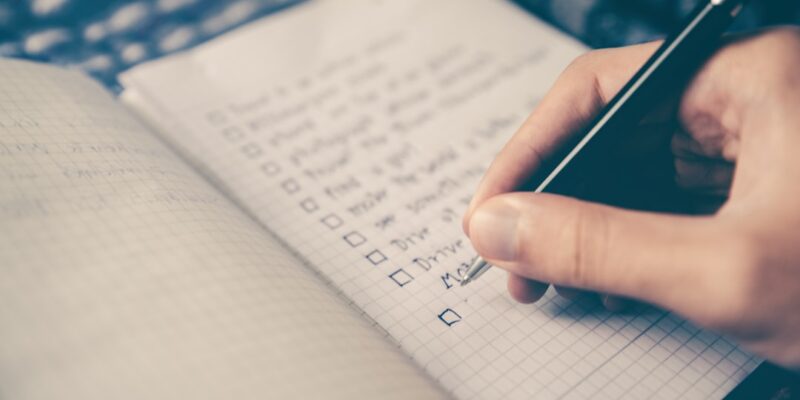 A person writing on a notebook with a pen.