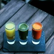 Three glasses of juice sitting on a wooden table.