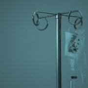 An iv bag on a stand against a blue background.