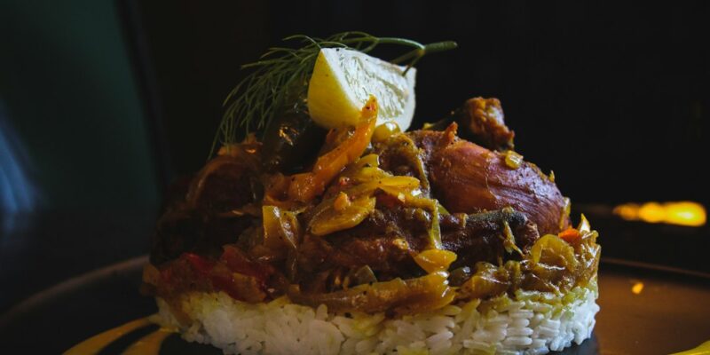 A plate of rice with chicken on top of it.