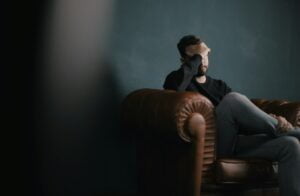 A man sitting on a leather chair in a dark room.