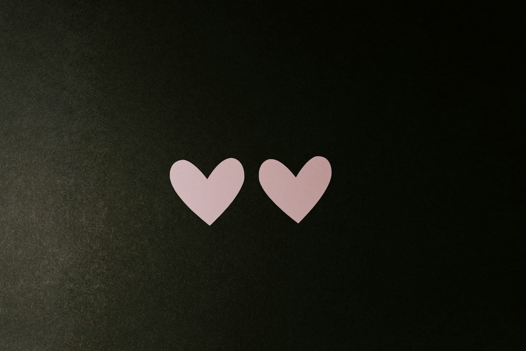 Two pink hearts on a black surface.