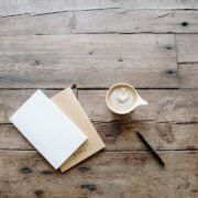 A cup of coffee and a notebook on a wooden table.