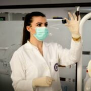 A woman wearing a lab coat and gloves in a laboratory.