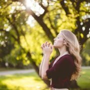 A young woman praying in a park.