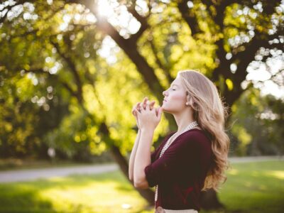 A young woman praying in a park.