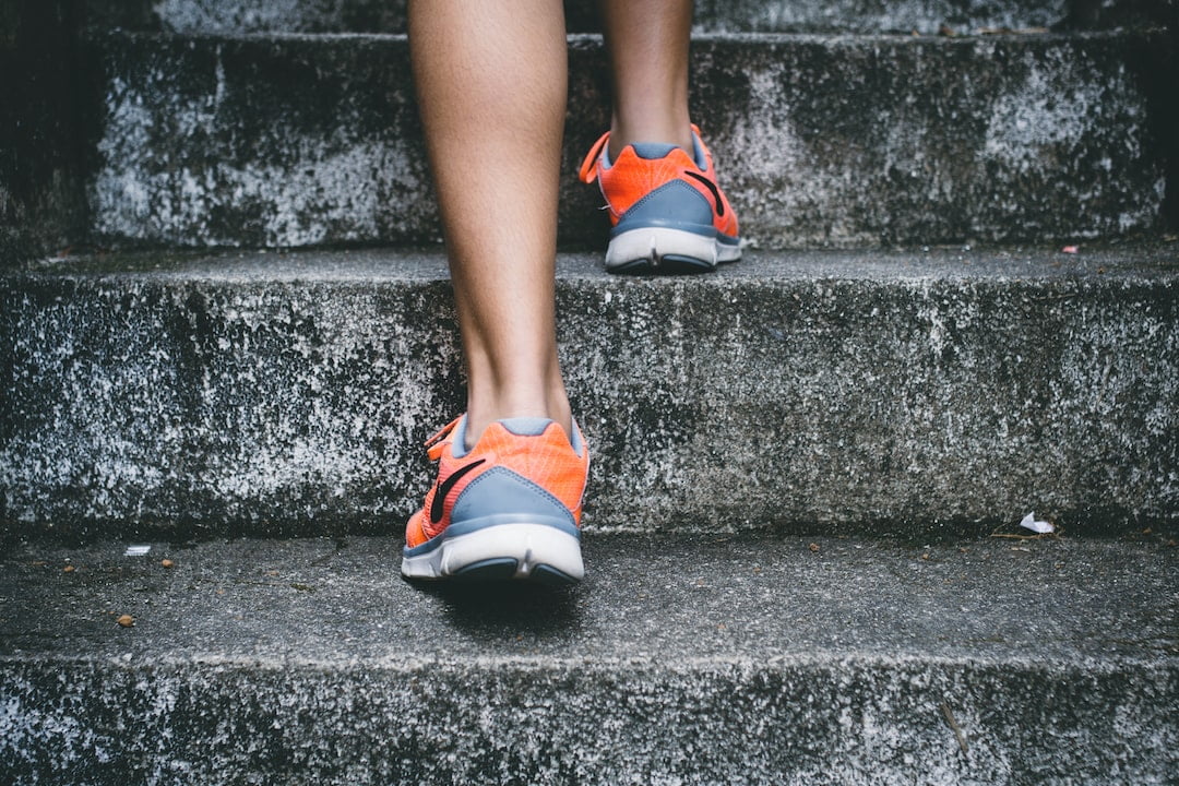 A person's legs and shoes on a concrete staircase.