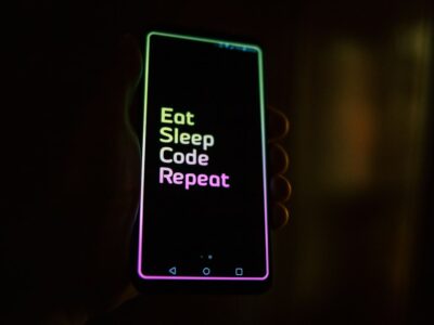 A person holding a phone that says eat sleep code repeat.