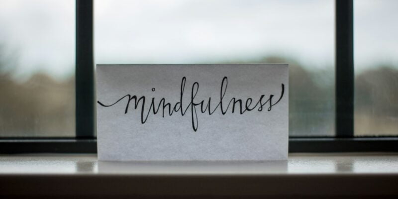 A piece of paper with the word mindfulness sitting on a window sill.