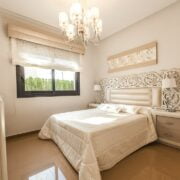 A bedroom with a white bed and a chandelier.