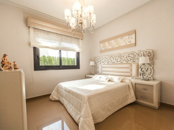 A bedroom with a white bed and a chandelier.