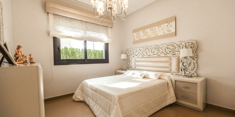 A bedroom with a white bed and a chandelier.