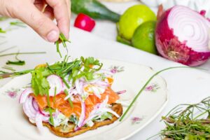 A person is preparing a sandwich on a plate with vegetables on it.