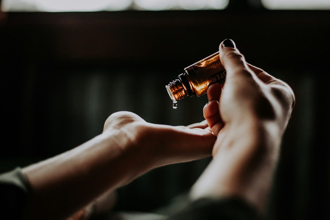 A person's hand holding an essential oil bottle.