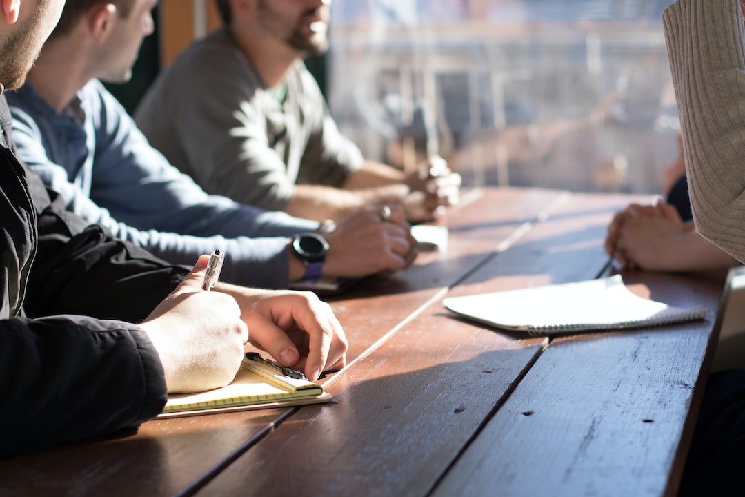 A group of people sitting at a table writing on notebooks.