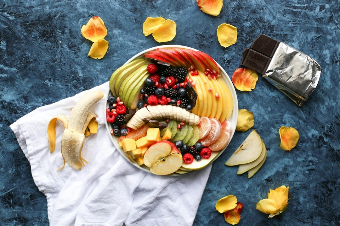 A plate of fruit and chocolate on a blue background.