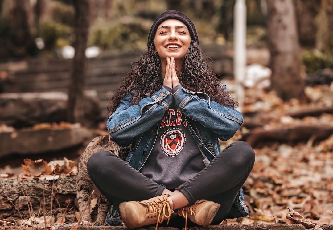 A woman sitting cross legged with her hands together.