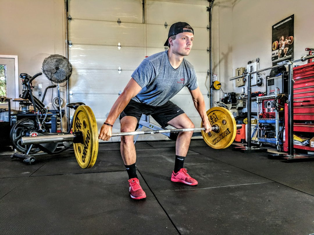 A man squatting with a barbell in his garage.