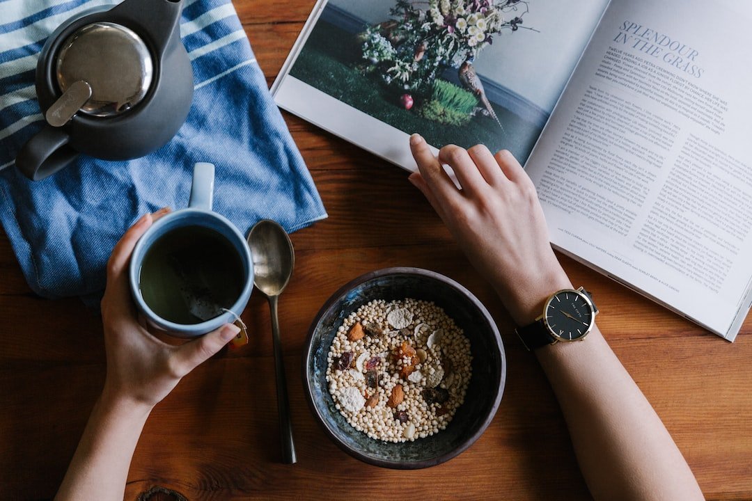 A person holding a cup of coffee and a bowl of cereal.