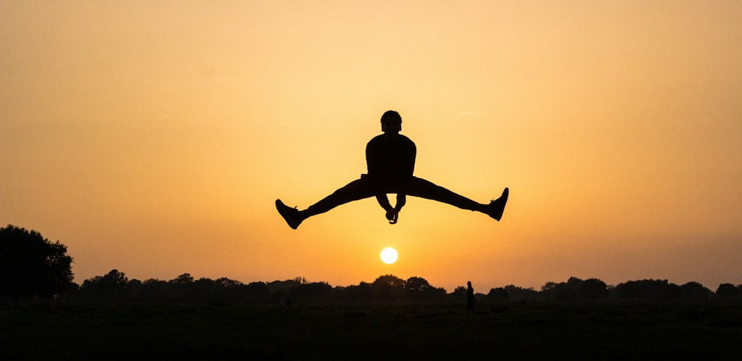 A silhouette of a man jumping in the air.