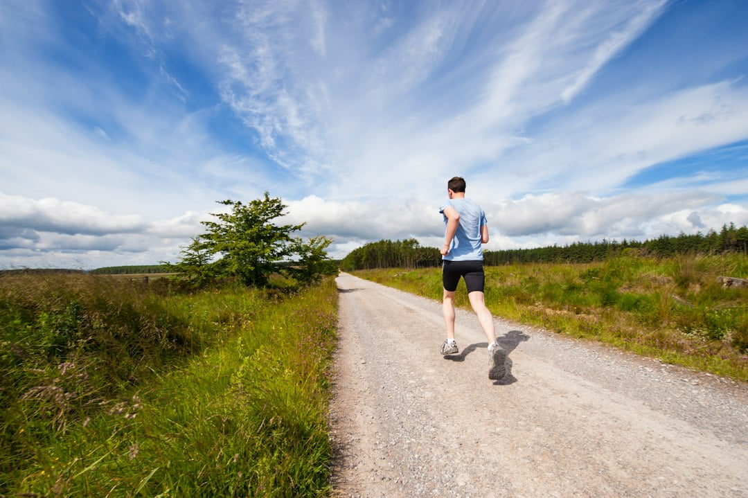 A man is jogging down a dirt road.